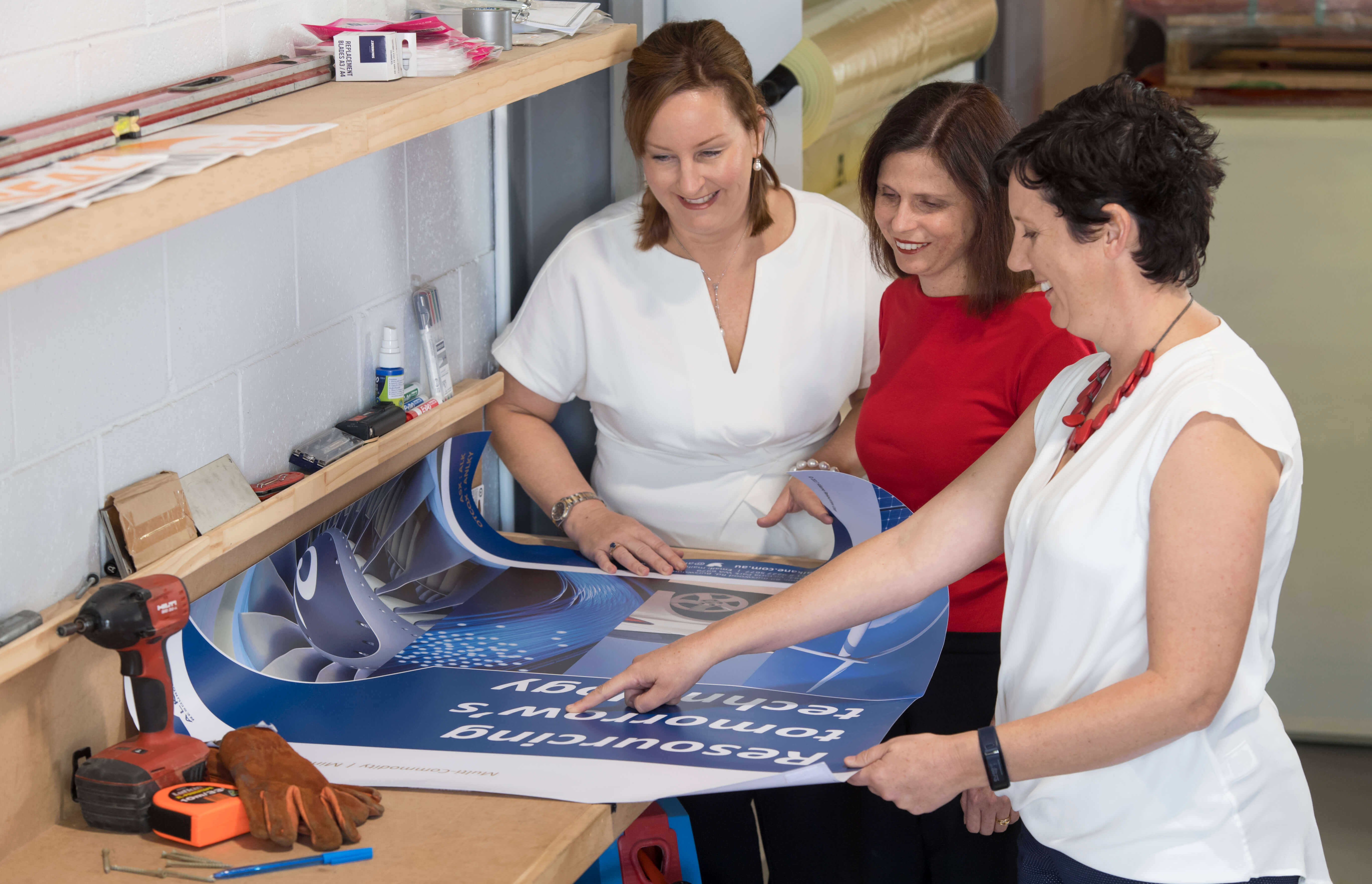 Women in STEM: Three woman look at a blue poster on working table 