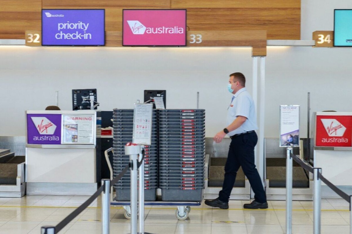 An employee walks past the empty check-in counters for Virgin Australia in the departures area at Adelaide Airport in Adelaide on April 21, 2020. Source: Brenton Edwards/