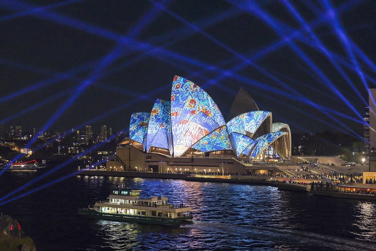 Ferries sail past the Sydney Opera House as it is illuminated with projections and lights at the start of the annual Vivid Sydney festival in Sydney on May 24, 2024. (Photo by DAVID GRAY / )