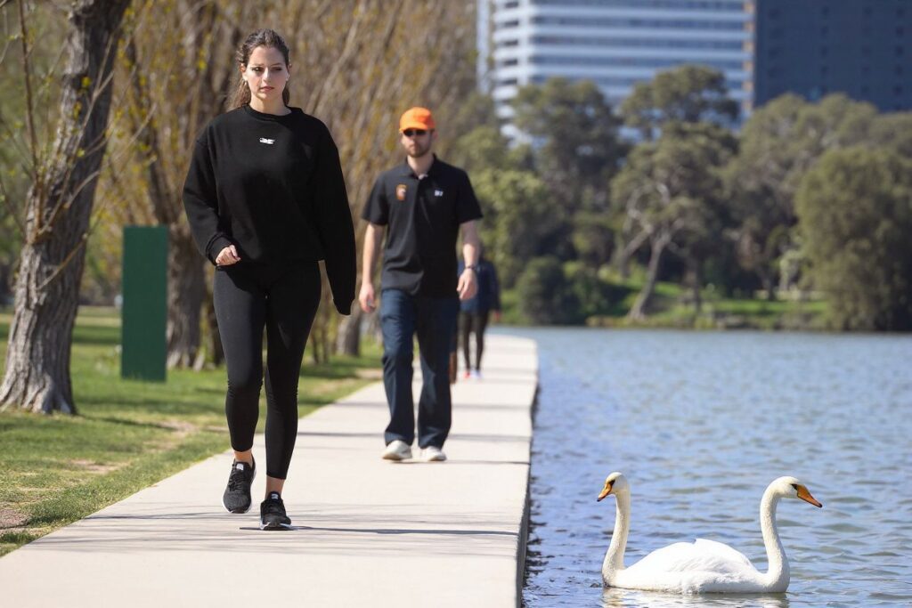 A woman passes a swan while exercising in Melbourne on September 16, 2021, as the state government announced a loosening of Covid-19 restrictions. (Photo by William WEST / )