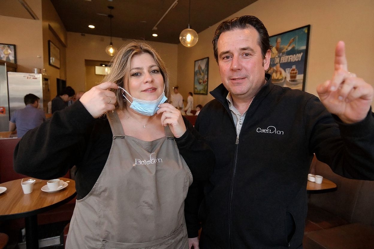 Cafe owner Chris Kriketos and his wife Adamantia Kriketos pose for pictures at their cafe on October 11, 2021, as Sydney ended their lockdown against the Covid-19 coronavirus after 106 days and restaurants began throwing open their doors to anyone who could prove they were vaccinated. (Photo by Saeed KHAN / )
