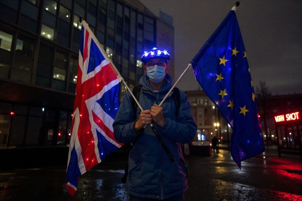 An anti-Brexit protester stands with Union and Eu flags outside a conference centre in central London on December 4, 2020, as talks continue on a trade deal between the EU and the UK. – With just a month until Britain’s post-Brexit future begins and trade talks with the European Union still deadlocked, the UK government on Tuesday urged firms to prepare as it scrambles to finish essential infrastructure. (Photo by Niklas HALLE’N / )