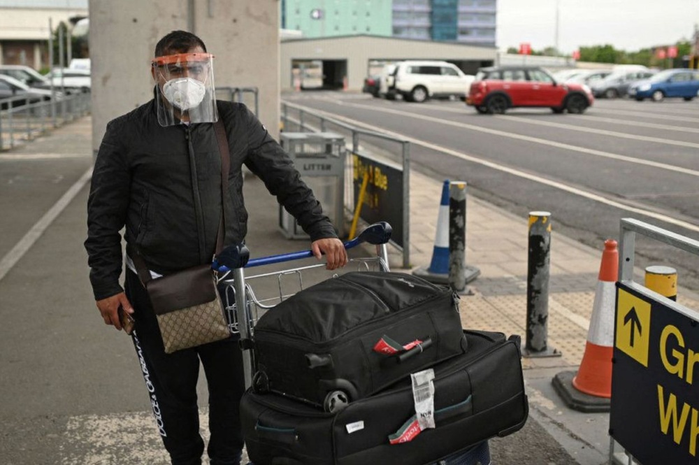 A passenger wearing PPE (personal protective equipment), including a face mask and a full face visor as a precautionary measure against COVID-19 upon arrival at Manchester Airport. Source: Oli Scarf/