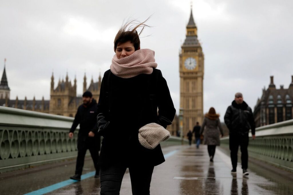 People struggle in the wind as they walk across Westminster Bridge, near the Houses of Parliament in central London, on February 18, 2022, as Storm Eunice brings high winds across the country. – Britain put the army on standby Friday and schools closed as forecasters issued two rare “red weather” warnings of “danger to life” from fearsome winds and flooding due to the approaching storm Eunice. (Photo by Tolga Akmen / )