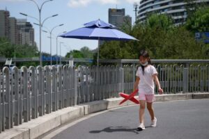 A girl (C) holding a toy plane walks on an overpass in Beijing on May 26, 2020. (Photo by WANG Zhao / )