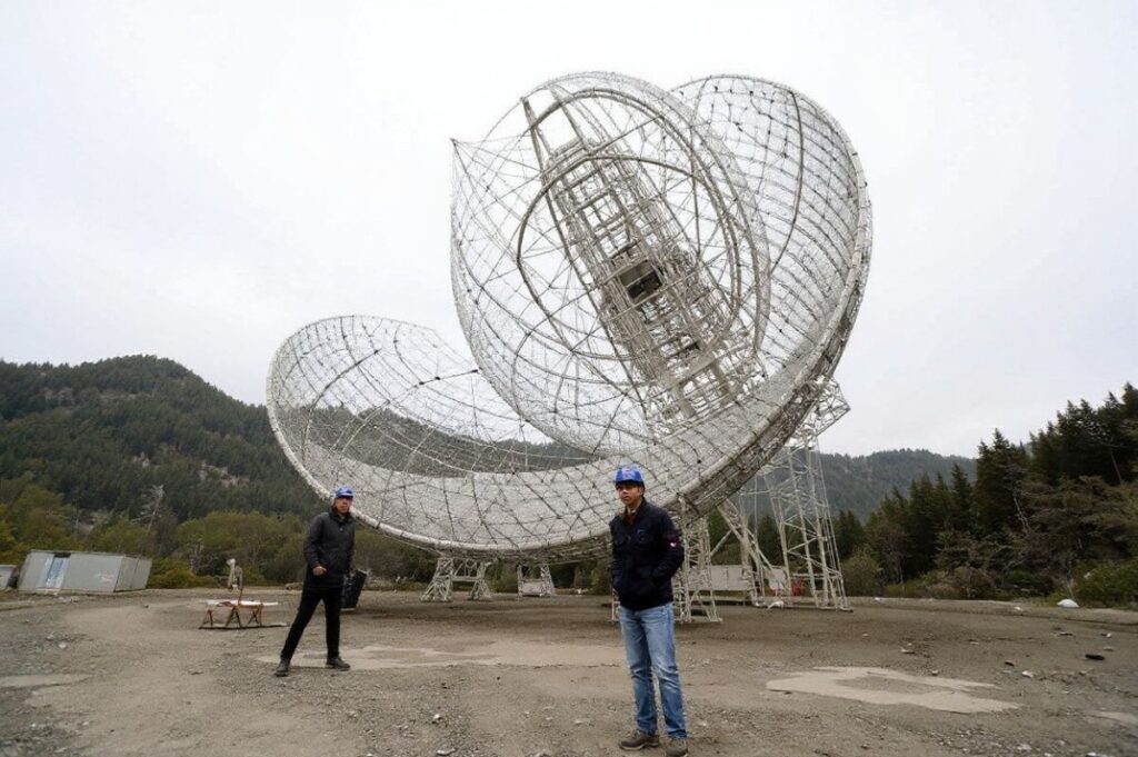 Sun Jinghai (C), director of Measurement and Control in the engineering department of the Five-hundred-meter Aperture Spherical radio Telescope (FAST), standing under the telescope during maintenance operations at the National Astronomical Observatories of the Chinese Academy of Sciences (NAOC) in Pingtang county in Guizhou, southwest China. Source: Noel Celis/