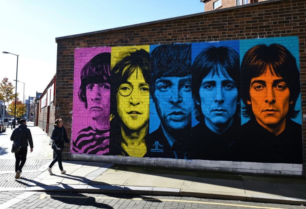 (FILES) Pedestrians pass a mural depicting members of British rock band The Beatles (L-R) Ringo Starr, John Lennon, Paul McCartney and George Harrison on the side of a building in Liverpool, northwest England on October 13, 2020, as new local lockdown measures are set to be imposed to help stem a second wave of the novel coronavirus COVID-19. A new Beatles song produced with a little help from artificial intelligence and including the vocals of John Lennon will be released on November 2, 2023, more than four decades after it was originally recorded as a demo. “Now And Then”, first written and sung by Lennon in 1978, was finished by his fellow band members Paul McCartney and Ringo Starr — and AI. (Photo by Paul ELLIS / )