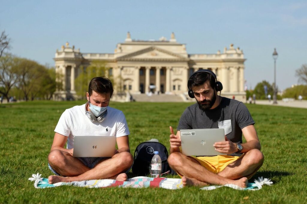 Two men on their computer on the grass on a sunny spring day in front of the Hotel des Invalides in Paris. Source: Bertrand Guay /