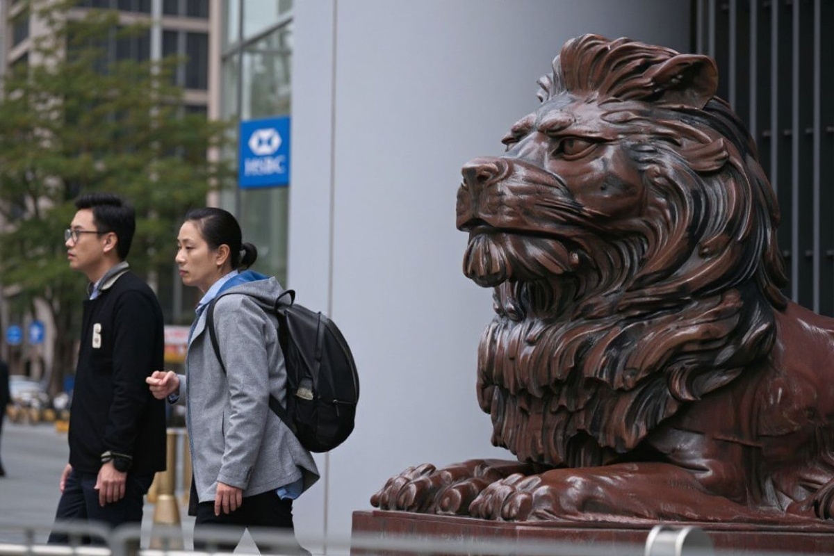 People walk past one of two bronze lions outside the HSBC building in Hong Kong on February 19, 2025, ahead of their annual results announcement. (Photo by Peter PARKS / )