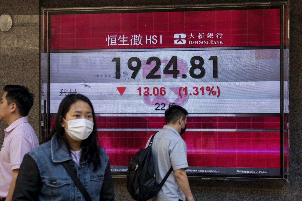 People walk past an electronic sign displaying the Hang Seng index in Hong Kong on March 16, 2023. – Hong Kong stocks tumbled at the open March 16 as concerns about credit giant Credit Suisse fuelled further bank contagion fears and traders nervously eyed next week’s Federal Reserve policy meeting. (Photo by ISAAC LAWRENCE / )