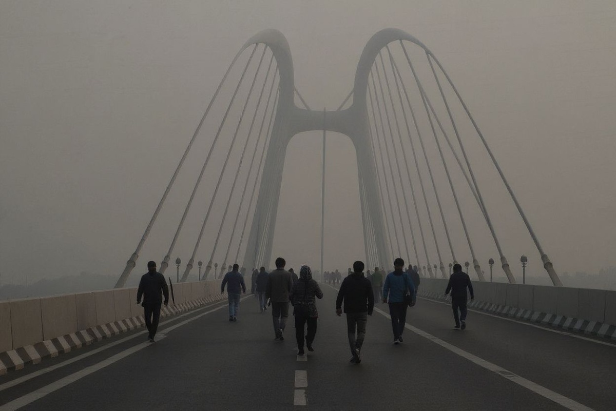 Commuters make their way through the Signature Bridge over the Yamuna River on a smoggy winter morning in New Delhi on December 20, 2024. (Photo by Arun SANKAR / )
