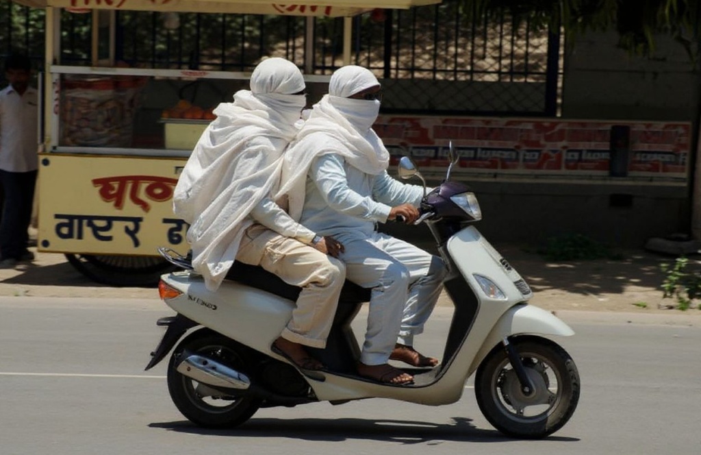 Indian commuters wrapped in cloth to protect them from the schorching heat ride a scooter in Allahabad on June 7, 2010. Northern India has been suffering from record high temperatures in a deadly heatwave which has reportedly caused 156 deaths.   PHOTO/Diptendu DUTTA (Photo by DIPTENDU DUTTA / )
