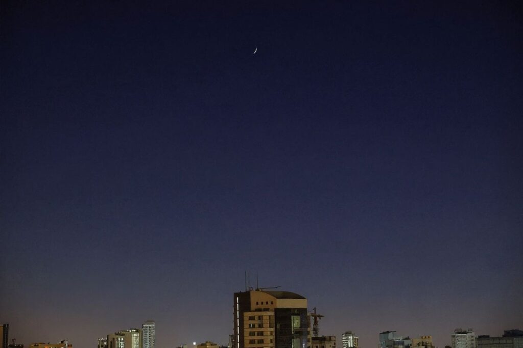 This picture taken on March 24, 2023 from Kuwait City shows a view of the waxing crescent moon and Venus (bottom) following a lunar occultation of the second planet from the sun. (Photo by YASSER AL-ZAYYAT / )