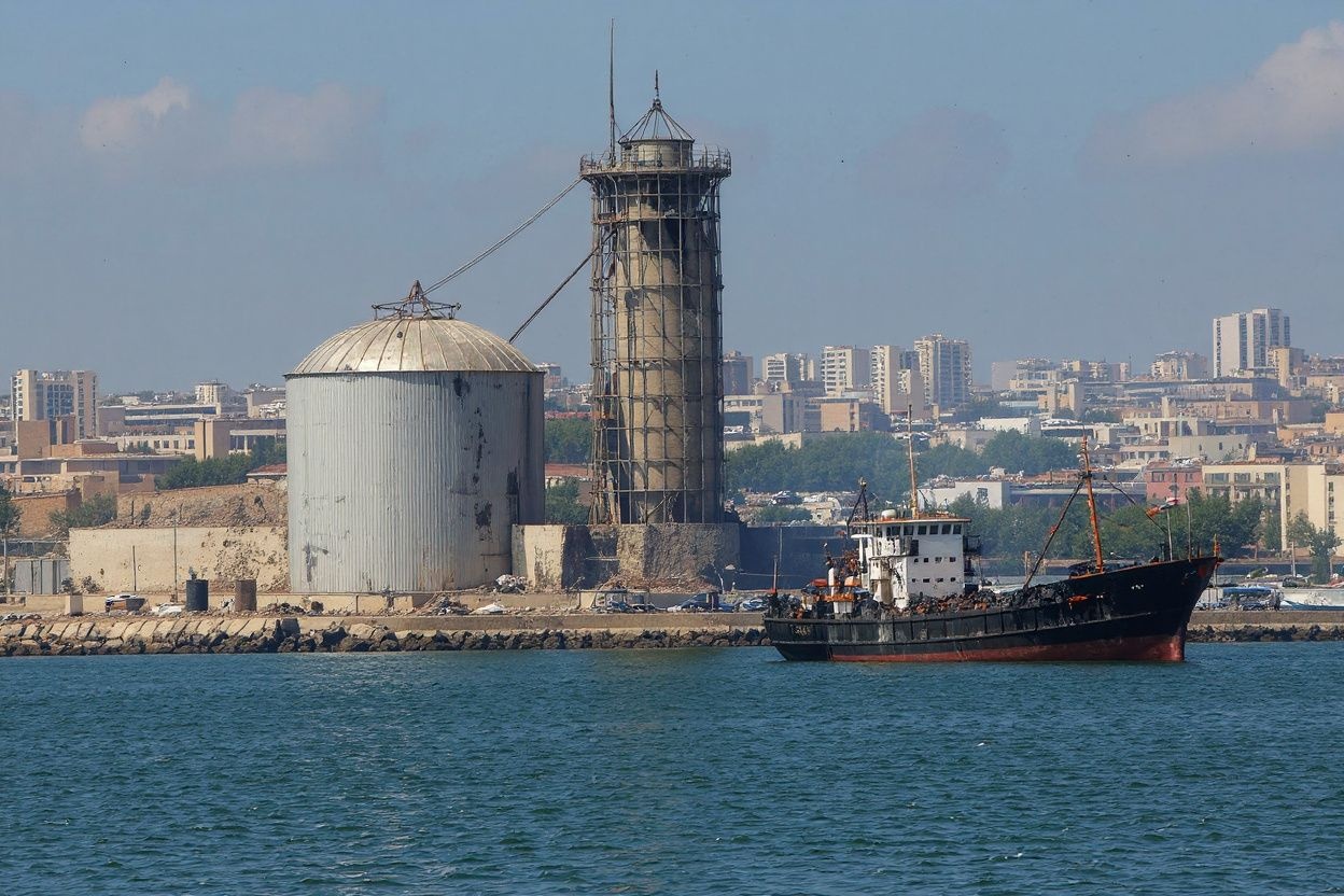 A picture taken on August 5, 2020 shows the damaged grain silo and a burnt boat at Beirut’s harbour, one day after a powerful twin explosion tore through Lebanon’s capital, resulting from the ignition of a huge depot of ammonium nitrate at the city’s main port. Source: STR/