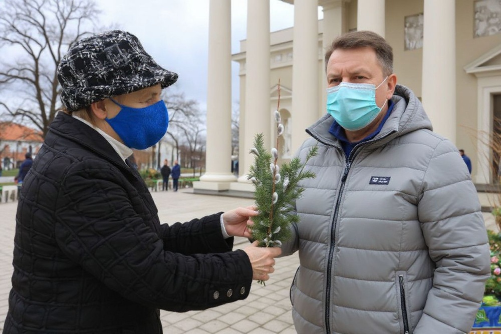 A woman wearing a face mask buys decorated juniper twigs and palms before a Palm Sunday mass outside the church of St Peter and St Paul in Vilnius, Lithuania, on March 28, 2021, amid the novel coronavirus / COVID-19 pandemic. Source: Petras Malukas/