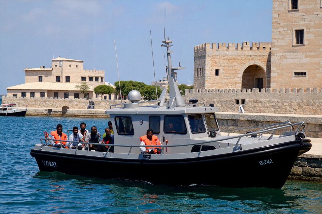 Migrants, part of group of 65 rescued by the German-flagged NGO rescue ship Alan Kurdi, sit in a patrol boat as they are brought into Haywharf, in Valletta, by the Armed Forces of Malta after being transferred onto the Maltese patrol boat on July 7, 2019. – Malta’s prime minister said on July 7 his country would relocate to other EU countries 65 migrants stranded aboard the Alan Kurdi rescue ship, after two other boats defied efforts to stop them landing in neighbouring Italy. The potential stand-off was averted after Malta agreed with the European Commission and Germany to take the migrants and transfer them to other EU countries. (Photo by Matthew Mirabelli / )