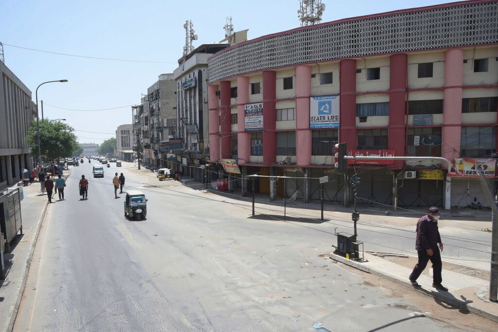 Commuters make their way through a partially deserted street during a nine-day nationwide lockdown imposed to curb the spread of the Covid-19 coronavirus in Karachi on May 15, 2021. (Photo by Rizwan TABASSUM / )