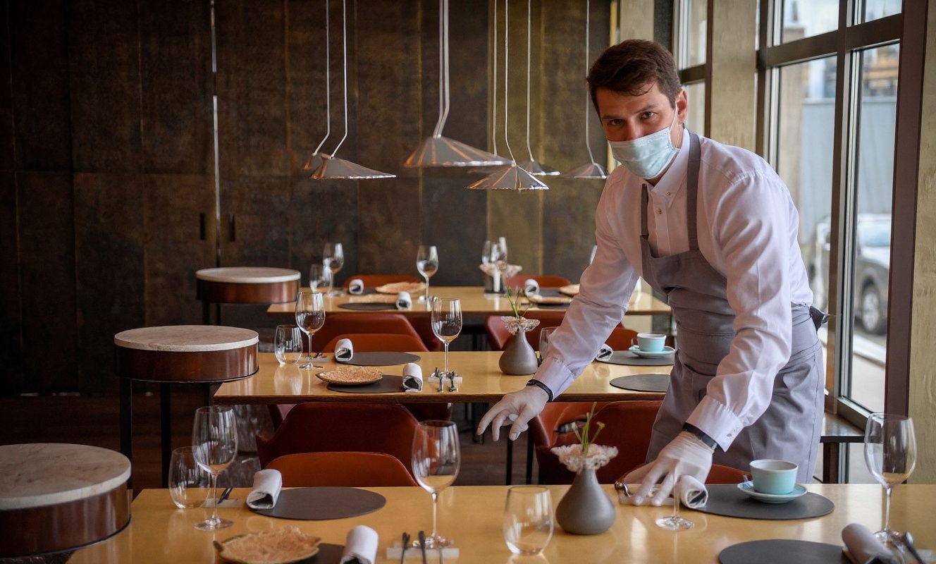 A waiter sets the tables in the dining area of Twins Garden restaurant run by Ivan and Sergey Berezutskiy in Moscow on October 15, 2021. – French gastronomic bible the Michelin Guide awarded nine Moscow restaurants with its coveted stars on October 14, 2021, unveiling its first lineup of recommended eateries in Russia’s up-and-coming food scene.  Two restaurants — Twins Garden run by twin brothers Ivan and Sergei Berezutskiy, and chef Artem Estafev’s Artest — were given two stars. (Photo by Alexander NEMENOV / )