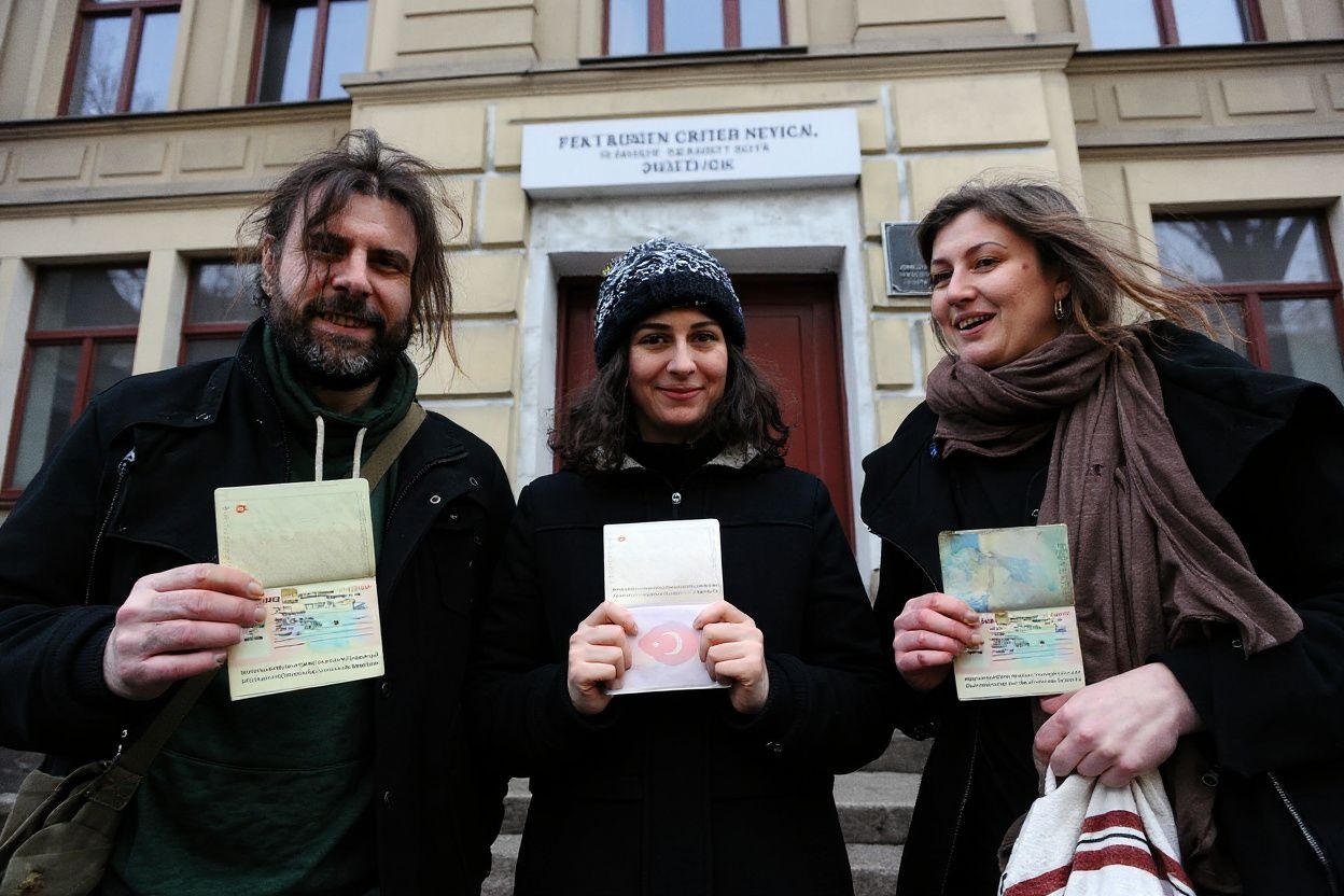 Greenpeace activists, members of the “Arctic 30,” (L-R)  Iain Rogers from United Kingdom, Gizem Akhan from Turkey  and Anne Mie Roer Jensen from Denmark, hold their passports with a Russian transit visa outside of the offices of the Federal Migration Service Department in St. Petersburg, on December 26, 2013. Last week Russian lawmakers approved a Kremlin-backed amnesty bill ending the prosecution of the so called Arctic 30, the Arctic Sunrise crew members, who had been held in detention since their September open-sea protest against Arctic oil drilling.  PHOTO / OLGA MALTSEVA (Photo by OLGA MALTSEVA / )