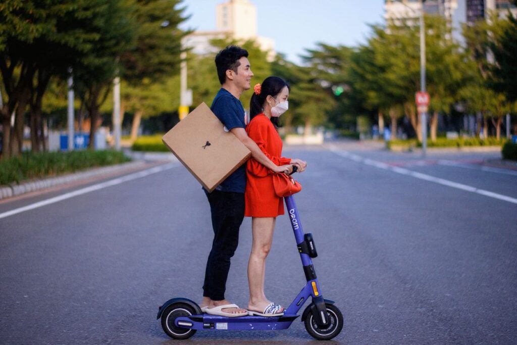 A man and woman ride an electric scooter on a road in Seoul on September 15, 2021. (Photo by Anthony WALLACE / )