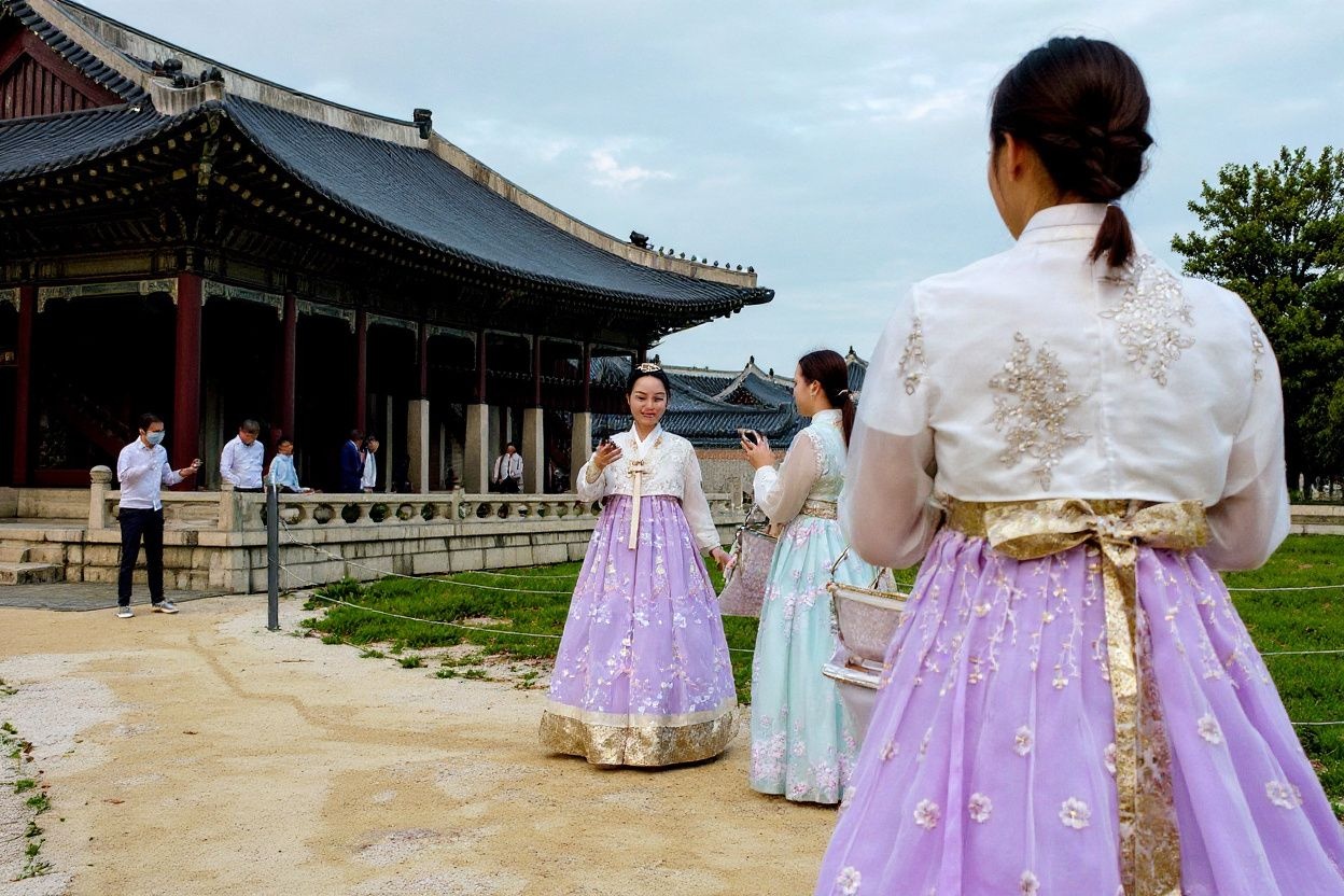 Visitors wearing traditional hanbok dresses take photos at the Gyeongbokgung Palace in Seoul on August 19, 2024. (Photo by Anthony WALLACE / )