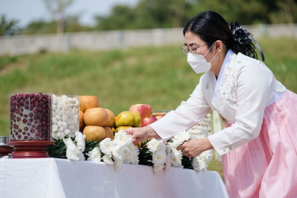 A woman wearing a traditional Hanbok dress places a white flower onto an altar with offerings for families with relatives and ancestors in North Korea, near the Demilitarized Zone (DMZ) separating North and South Korea, at the Imjingak ‘peace park’ in Paju on September 21, 2021, as South Koreans observe the annual ‘Chuseok’ thanksgiving holiday which runs from September 20 to 22. (Photo by Anthony WALLACE / )