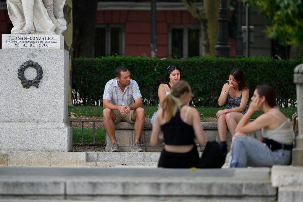 People sit in the shade to hide from the sun in Madrid on July 18, 2023. Spain issued hot weather red alerts for three regions due to the “extreme” danger posed by scorching temperatures as firefighters made gains in their battle against a blaze raging in the Canary Islands. Weather agency Aemet said temperatures would hit highs between 38 degrees Celsius (100 Fahrenheit) and 42 degrees across much of the drought-stricken country, sending people to seek shade from a blistering sun. (Photo by JAVIER SORIANO / )