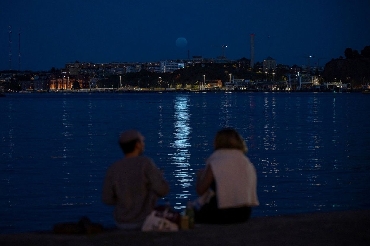 People watch as a Super Blue Moon rises behind Nacka, in Stockholm, on August 19, 2024. Source: