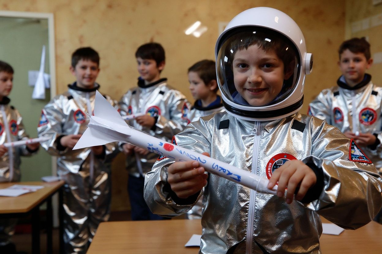 A pupil of the Ecole Vivalys elementary school, wearing a spacesuit costume, shows a self made paper rocket during their project Mission to Mars in Lausanne, on March 17, 2021. – While the world for the past month has been riveted by the escapades of the Perseverence Mars rover, a group of Swiss fourth-graders has been making final preparations for their own mission to the red planet. Source: Stefan Wermuth/