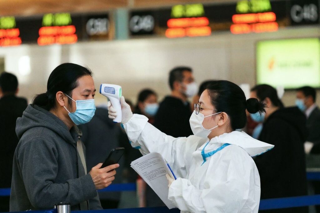 LOS ANGELES, CALIFORNIA – DECEMBER 22: A traveler receives a a temperature check before checking in for a China Airlines flight at the Tom Bradley International Terminal at Los Angeles International Airport (LAX) amid a COVID-19 surge in Southern California on December 22, 2020 in Los Angeles, California. TSA agents screened over 1 million people for three consecutive days last Friday, Saturday and Sunday, the beginning of the traditional holiday travel season, for the first time since the start of the coronavirus pandemic.   Mario Tama/Getty Images/ (Photo by MARIO TAMA / GETTY IMAGES NORTH AMERICA / Getty Images via )