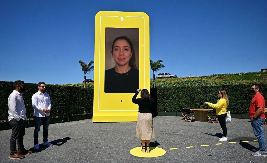 A woman stands on the yellow spot to view herself in the AR Mirror as people attend the 2023 Snap Partner Summit at the Barker Hangar in Santa Monica, California, on April 19, 2023 where the focus was on immersive augmented reality experiences and tech for people attending music concerts. (Photo by Frederic J. BROWN / )