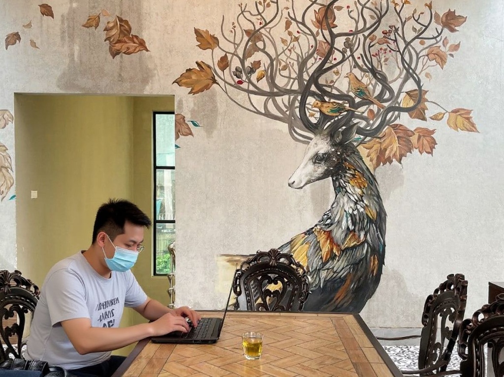 A man plays games on his laptop at a cafe in Hanoi on October 19, 2021. (Photo by Manan VATSYAYANA / )
